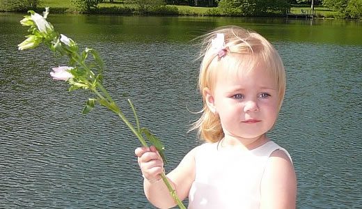 Child with flower by water
